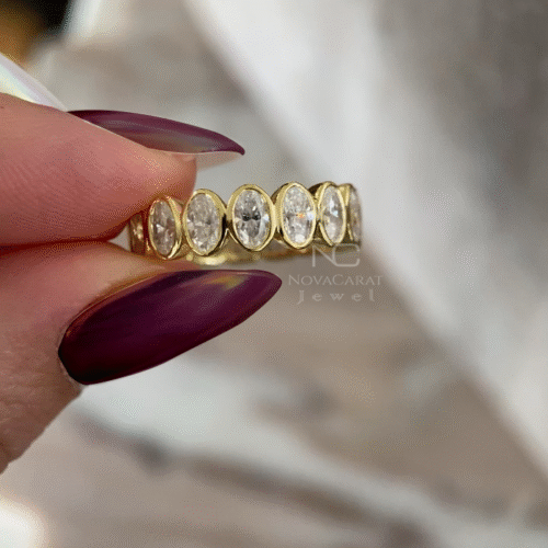 Studio Light Shot: Studio-lit shot of oval cut moissanite eternity ring, bezel set full diamond wedding band in Yellow gold, designed as a modern anniversary ring and fine stacking jewelry for women. Bezel Set Oval Moisanite Diamond Wedding Band, Full Eternity Diamond Engagement Band, 14k Yellow gold oval Cut diamond band, Anniversary gift, Gift for Her, Oval Moissanite Half Eternity Women's Engagement Band, Bezel Set Band For Her, Moissanite Oval Cut Bezel Set Eternity Band, Moissanite Oval Cut Wedding Ring