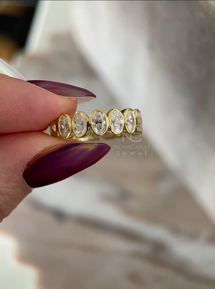 Studio Light Shot: Studio-lit shot of oval cut moissanite eternity ring, bezel set full diamond wedding band in Yellow gold, designed as a modern anniversary ring and fine stacking jewelry for women. Bezel Set Oval Moisanite Diamond Wedding Band, Full Eternity Diamond Engagement Band, 14k Yellow gold oval Cut diamond band, Anniversary gift, Gift for Her, Oval Moissanite Half Eternity Women's Engagement Band, Bezel Set Band For Her, Moissanite Oval Cut Bezel Set Eternity Band, Moissanite Oval Cut Wedding Ring