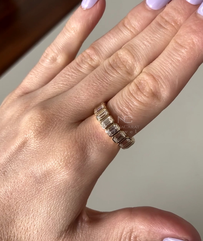 Studio lit shot of emerald cut moissanite diamond eternity band, bezel set stones in Yellow gold, minimalist yet luxurious stacking wedding ring perfect for anniversaries. Emerald cut moissanite eternity band in 14k gold. Bezel set minimalist stacking ring, perfect bridal wedding band, promise or anniversary gift. Anniversary Band, Gift For Her, Diamond Bridal Band, Emerald Cut Stackable Band, Anniversary Gift for Her, Unique Art Deco Eternity Band, Full Eternity Bezel set Emerald Cut Diamond
