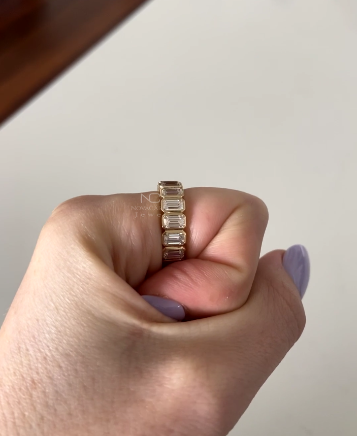 Side profile of emerald cut moissanite wedding band, sleek bezel setting in Yellow gold, crafted as a stackable bridal diamond band and timeless anniversary jewelry for her. Diamond Wedding Band Stackable Band Emerald Minimalist Band, Emerald Cut Moissanite Diamond ring, Bezel Set Emerald Cut Eternity Band, 14K Yellow Gold Wedding Band Stackable Band Emerald Minimalist Band Anniversary Ring, Stackable Bridal Diamond Band, Emerald Moissanite, Promise Ring, Stackable Bridal Diamond Band