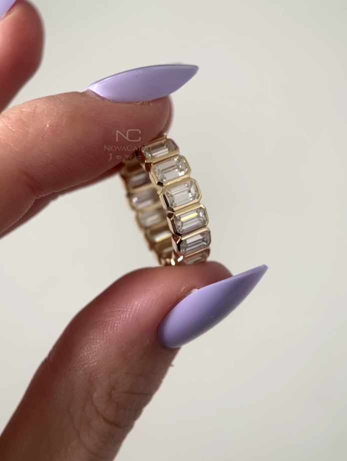 Back view of emerald cut moissanite anniversary band, bezel set eternity ring in yellow gold, stackable and elegant diamond band perfect for bridal and wedding celebrations. Moissanite Diamond Emerald Cut Eternity Band, Yellow Gold Stacking Band, Emerald Cut Lab Diamond Eternity Ring, Bezel Set Emerald Cut Eternity Band, Lab Diamonds Wedding Band, Emerald Cut Moissanite Diamond Half Eternity Band, Bezel Set 14K Yellow Gold Wedding Ring, Emerald Cut Diamond Simulant Eternity Band, 14k Gold